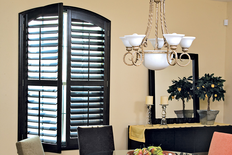 Dark wood Ovation shutters in a small dining room area.
