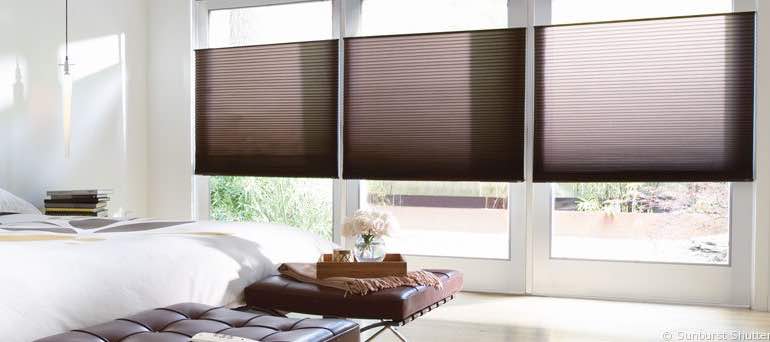 Chic Houston bedroom with high windows and brown honeycomb shades.