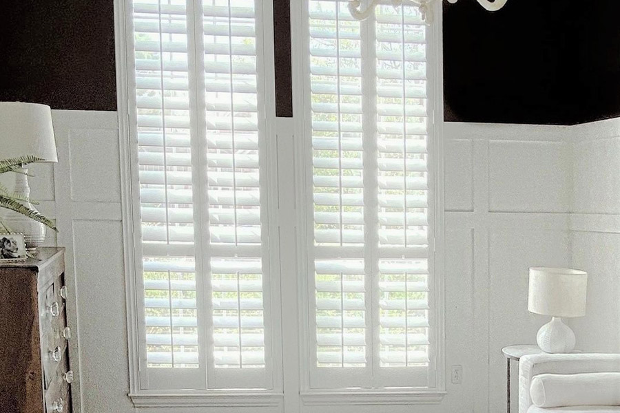 White and black sleek living room with long white polywood shutters