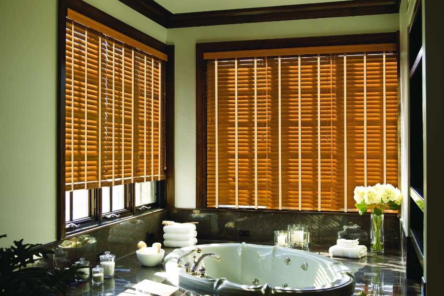 Premium quality blinds are always a stylish accent in your Houston home. Brown wood blinds on large windows in a green bathroom