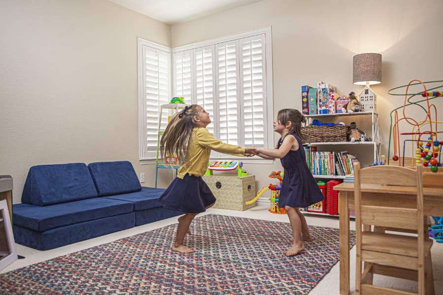 Choose Polywood shutters for durable, kid-friendly great room window treatments in Houston. Polywood shutters on multiple windows in a sitting area