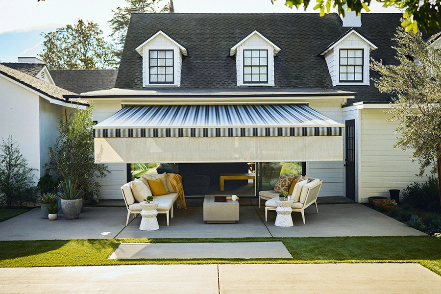 Get more use out of your deck or patio each summer when you install an awning for cool shade. A back patio with furniture and a striped awning over it