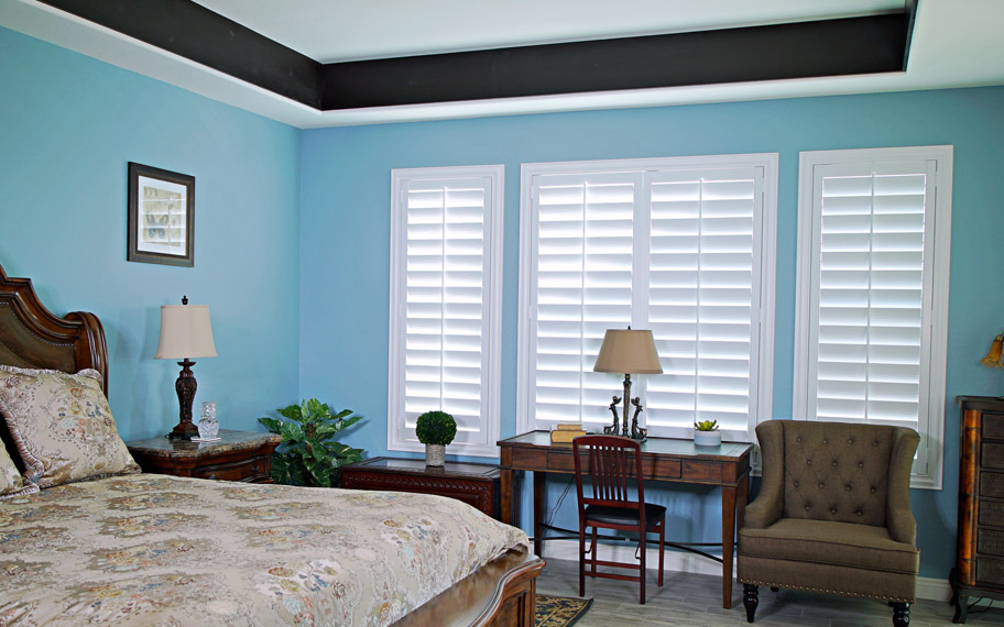 Polywood shutters provide insulation for the perfect temperature all year long in Houston. Polywood shutters in a bedroom.