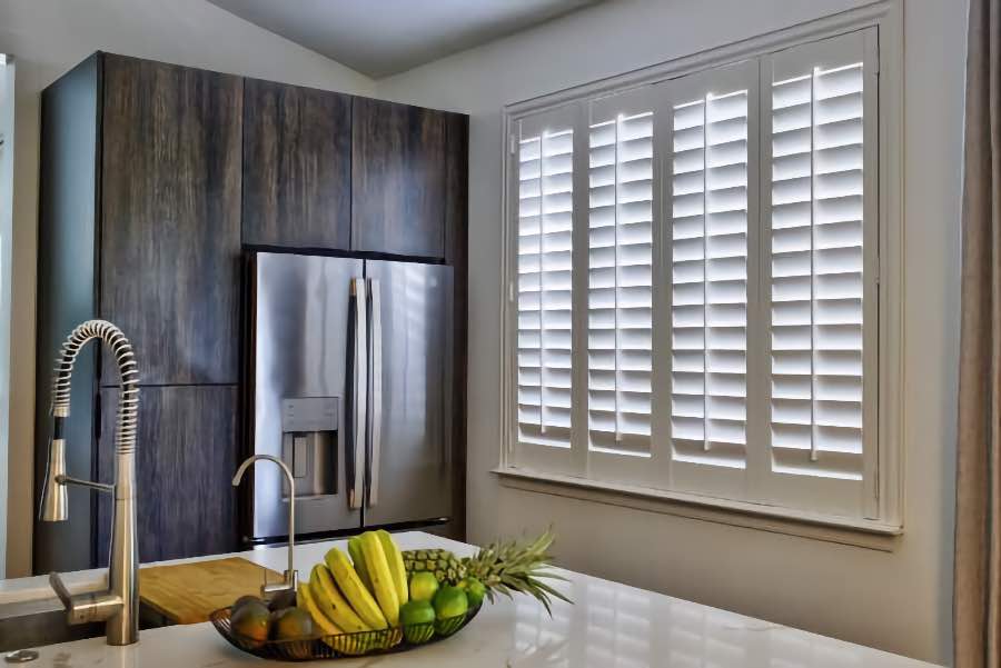 Homeowners use indoor window shutters in Houston when they want attractive and functional window treatments. Polywood shutters on a large kitchen window