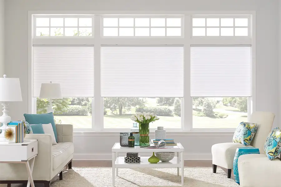 Insulating cellular shades can help keep cold air and hot UV rays from entering your Houston home. White cellular shades on windows in a white living room